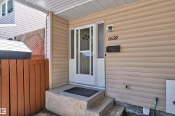 Entryway featuring concrete steps, a white storm door, beige horizontal siding, a black mailbox, and numerical house address - 