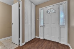 Entryway featuring a paneled white door with an arched transom window and textured glass sidelights - 