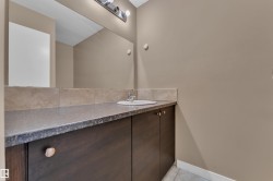 Vanity area featuring an integrated sink, dark wood-finish cabinetry with circular hardware, and a stone-look countertop - 