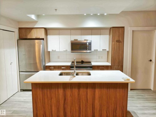 Modern kitchen featuring a central island with dual sinks and white countertop - 2505 10410 102 Avenue, Edmonton, AB 