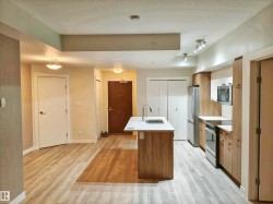 Kitchen featuring a center island with sink, stainless steel appliances, wood-finish cabinetry, and light countertops - 