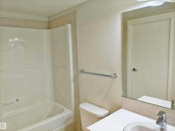 Bathroom featuring a white bathtub with a shower surround, a white toilet, and a vanity with a drop-in sink and chrome faucet - 