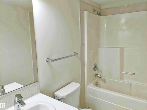 Bathroom featuring a white vanity with an integrated sink, chrome faucet, and a subway tile backsplash - 2505 10410 102 Avenue, Edmonton, AB 