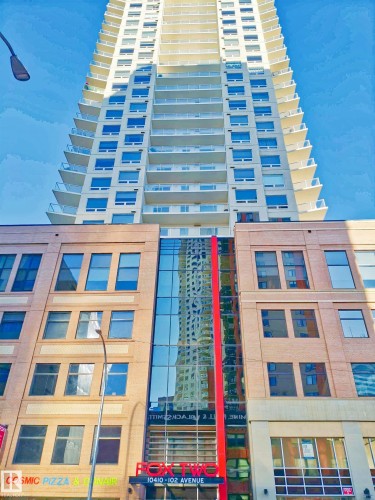 Modern high-rise building featuring a multi-story base with brick and glass facades, topped by a tall residential tower - 2505 10410 102 Avenue, Edmonton, AB 