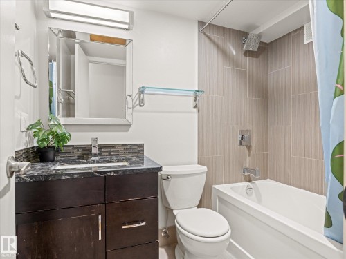 Bathroom featuring a dark wood-finish vanity with a dark countertop, undermount sink, and tiled backsplash - 1601 9725 106 Street, Edmonton, AB 