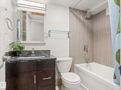 Bathroom featuring a dark wood-finish vanity with a dark countertop, undermount sink, and tiled backsplash - 