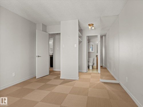 Room featuring checkered carpet flooring, light gray walls, white baseboards, and a white ceiling - 1601 9725 106 Street, Edmonton, AB 