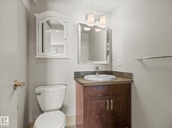 Bathroom featuring a wood-finish vanity with an integrated sink, mosaic tile backsplash, and a contemporary wall-mounted light fixture - 