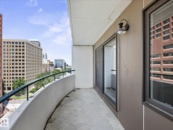 Curved concrete balcony featuring a metal railing and city architecture - 