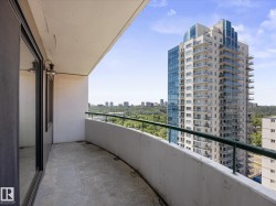 Curved concrete balcony featuring a green metal railing and an exterior light fixture - 