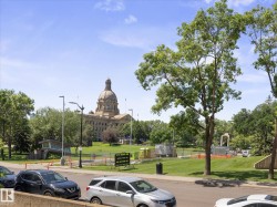 Grand historical architecture with a prominent dome, surrounded by expansive green parkland and mature trees - 