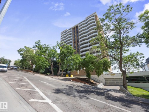 High-rise building with numerous private balconies, a brown and white exterior, and a visible underground parking garage entrance - 1601 9725 106 Street, Edmonton, AB 