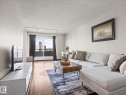 Living space featuring wood-finish flooring, light-colored walls, and a large window with sliding door access to an exterior balcony - 1601 9725 106 Street, Edmonton, AB 