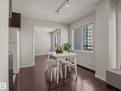 Dining area featuring rich wood-finish flooring, light gray walls, and a large window - 