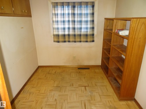Room featuring wood-finish parquet flooring, a window, and built-in wood cabinetry - 5036 52 Street, Andrew, AB 