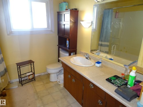 Bathroom featuring a white single-hung window, light yellow walls, and a ceramic tile floor - 5036 52 Street, Andrew, AB 