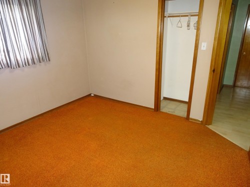 Carpeted room with neutral wall tones and wood trim - 5036 52 Street, Andrew, AB 