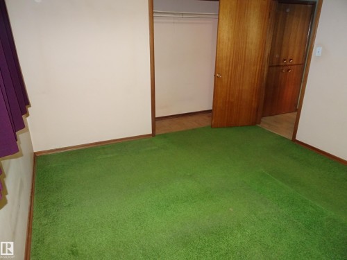 Green carpeted flooring with wood-finish baseboards - 5036 52 Street, Andrew, AB 