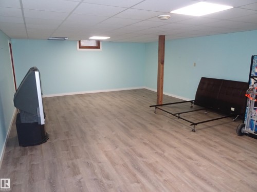 Spacious room featuring wood-finish flooring, light blue walls, and a drop ceiling with integrated lighting - 5036 52 Street, Andrew, AB 