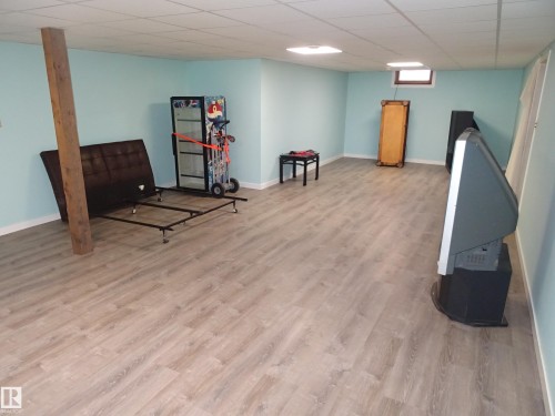 Spacious room featuring wood-finish flooring, a drop ceiling with recessed lighting, and light blue walls with white trim - 5036 52 Street, Andrew, AB 
