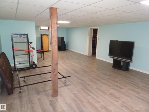 Spacious room featuring light blue walls, wood-finish flooring, and a white drop ceiling - 5036 52 Street, Andrew, AB 