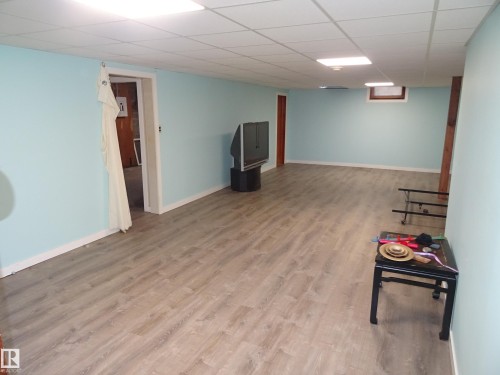 Spacious room featuring wood-finish flooring, light blue walls, and a white drop ceiling with recessed lighting - 5036 52 Street, Andrew, AB 