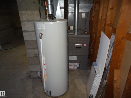 Utility area with a water heater and a Lennox furnace, featuring exposed wooden framing and concrete block walls - 5036 52 Street, Andrew, AB 