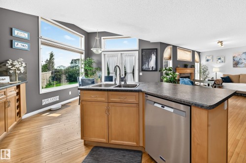 Kitchen featuring light wood cabinetry, a stainless steel dishwasher, and a dual basin sink with a high-arch faucet - 8507 179 Avenue, Edmonton, AB 