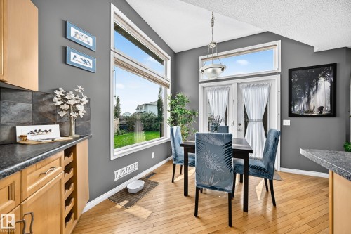 Dining area featuring hardwood flooring, vaulted ceiling, and a large picture window with a transom - 8507 179 Avenue, Edmonton, AB 