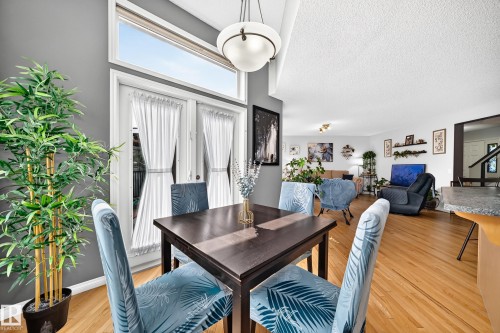 Dining area featuring wood-finish flooring, a contemporary overhead light fixture, and a dark wood-finish dining table - 8507 179 Avenue, Edmonton, AB 