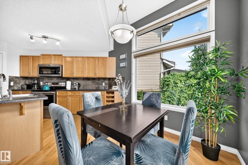 Dining area featuring a large picture window with transom, wood-finish flooring, and a contemporary pendant light - 8507 179 Avenue, Edmonton, AB 