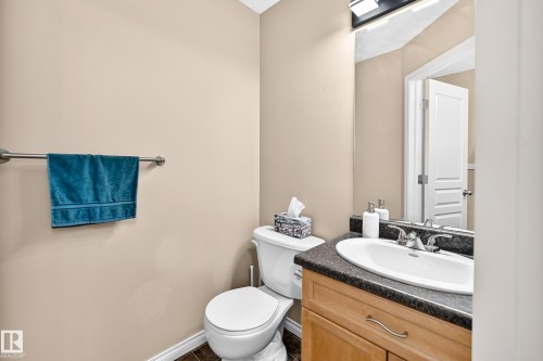 Vanity with a white oval sink, dark countertop, and wood-finish cabinetry - 8507 179 Avenue, Edmonton, AB 