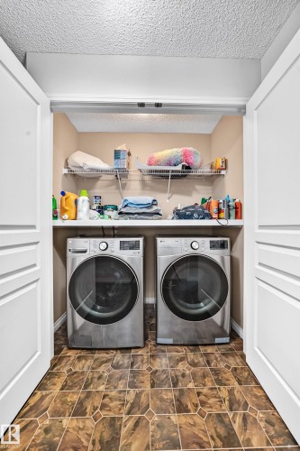 Dedicated laundry closet featuring a side-by-side washer and dryer, built-in wire shelving, and patterned flooring - 8507 179 Avenue, Edmonton, AB 