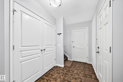 Entryway featuring patterned brown flooring, white paneled doors, white trim, and a ceiling-mounted light fixture - 8507 179 Avenue, Edmonton, AB 