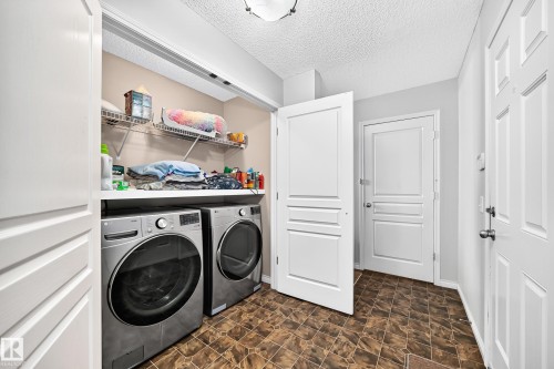 Dedicated laundry area featuring a front-loading washer and dryer, integrated countertop, and overhead wire shelving - 8507 179 Avenue, Edmonton, AB 