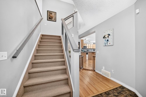 Carpeted staircase with light gray walls, white trim, and a high ceiling - 8507 179 Avenue, Edmonton, AB 