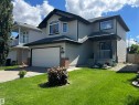 Two-story residence featuring light gray siding, dark trim, and a prominent arched window on the upper level - 8507 179 Avenue, Edmonton, AB 
