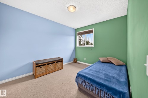 Carpeted room featuring a window with white trim, a built-in light fixture, and contrasting blue and green wall finishes - 8507 179 Avenue, Edmonton, AB 