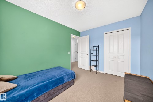 Bedroom featuring bi-fold closet doors, wall-to-wall carpeting, a flush mount ceiling light fixture, and a solid core interior door - 8507 179 Avenue, Edmonton, AB 