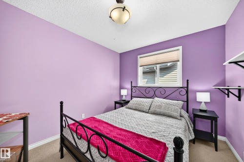 Bedroom featuring a window with a roller blind, carpet flooring, and a ceiling-mounted light fixture - 8507 179 Avenue, Edmonton, AB 