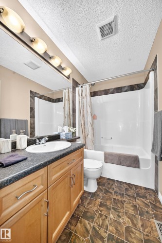 Bathroom featuring a built-in vanity with wood cabinetry, a dark countertop, and an undermount sink - 8507 179 Avenue, Edmonton, AB 