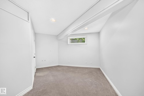 Carpeted room with a white door, recessed ceiling lighting, and a horizontal window featuring exterior foliage - 8507 179 Avenue, Edmonton, AB 