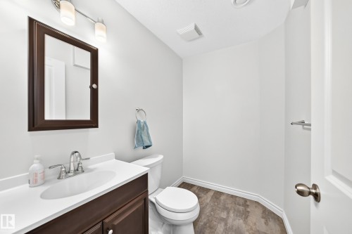 Well-appointed powder room featuring a single vanity with a white countertop and dark wood cabinetry - 8507 179 Avenue, Edmonton, AB 