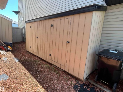Exterior storage shed with three hinged doors, featuring light-toned paneling and a dark-toned flat roof - 8507 179 Avenue, Edmonton, AB 