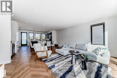 Open-concept living area featuring wood-finish flooring in a herringbone pattern and recessed lighting - 1304 Rutherford Road, Edmonton, AB 