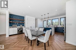 Open-concept living space featuring wood-finish flooring with a herringbone pattern, a built-in beverage cooler, a kitchen island with pendant lighting, and multiple windows - 