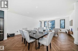Open-concept living space featuring wood-finish flooring with a herringbone pattern, recessed lighting, and expansive windows - 