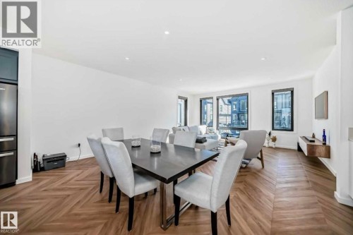 Open-concept living space featuring wood-finish flooring with a herringbone pattern, recessed lighting, and expansive windows - 1304 Rutherford Road, Edmonton, AB 