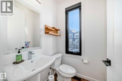 Contemporary bathroom featuring a pedestal sink with a chrome faucet, a rectangular mirror, and a narrow vertical window with black trim - 