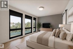 Modern bedroom featuring large windows with black frames, wood-finish flooring, a contemporary ceiling light fixture, and a sliding barn door - 